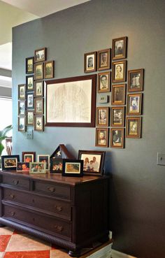 a dresser with many framed pictures on the wall