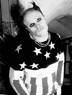 a woman with red hair and piercings wearing an american flag sweater posing for the camera