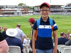 a young boy standing in front of a crowd at a baseball game wearing glasses and a hat