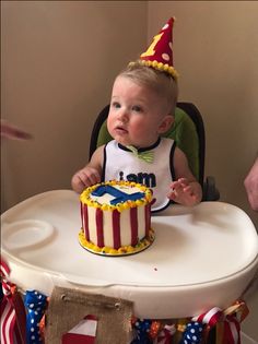 a baby sitting in a high chair with a birthday cake