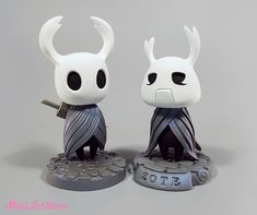 two white figurines with black eyes and horns