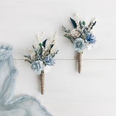 two boutonnieres with blue and white flowers are on the wall next to each other