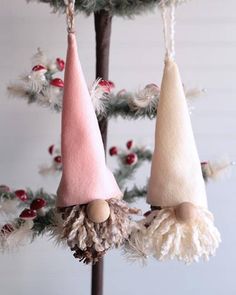 three gnome ornaments hanging from a tree with pine cones and pom - poms