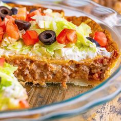 a taco pie with lettuce, tomatoes, black olives and other toppings