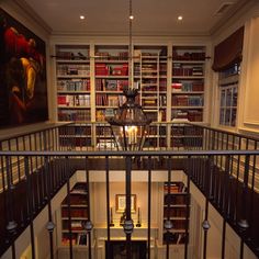 the stairs lead up to an open bookcase with many books on it and a chandelier hanging from the ceiling