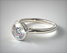 a close up view of a ring with a diamond in it on a white surface