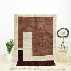 a brown and white rug sitting on top of a wooden floor next to a potted plant