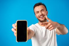 a man is holding up his cell phone and giving the thumbs up sign with both hands