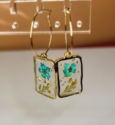 Clear resin with paper flower inside. Elegant Resin Flower-shaped Earrings, Elegant Resin Flower Earrings, Gold Floral Print Flower Earrings, Resin Flower Charm Drop Earrings, Resin Drop Earrings With Flower Charm, Handmade Resin Flower Shaped Earrings, Handmade Resin Flower-shaped Earrings, Gold Resin Flower Charm Earrings, Gold Flower Charm Earrings In Resin