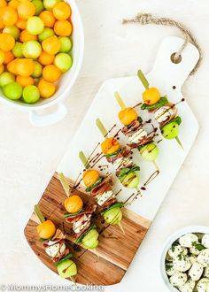 an appetizer is served on a cutting board next to bowls of oranges