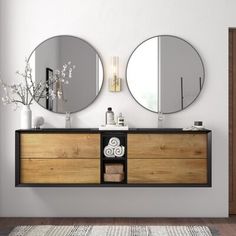 a bathroom with two mirrors on the wall and a wooden cabinet in front of it