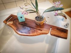 a bathroom sink with a wooden tray on the edge and flowers in vases sitting on it