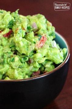 a bowl filled with guacamole on top of a wooden table