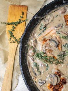 a skillet filled with mushroom soup next to a wooden spoon