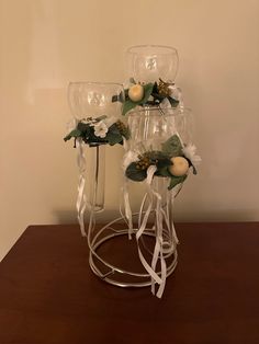 three wine glasses with flowers in them sitting on a table next to a glass vase