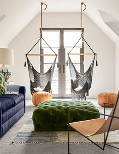 a living room with two hammocks hanging from the ceiling and chairs on the floor