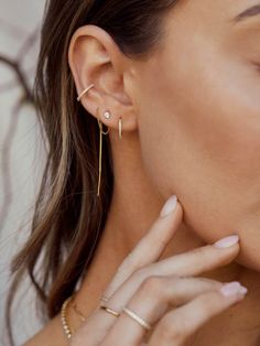 a close up of a person wearing ear rings and holding their hand to her ear