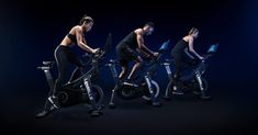 three people riding stationary bikes with laptops in their hands and one person on an exercise bike