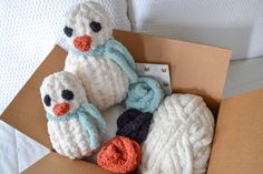 three knitted stuffed animals in a cardboard box