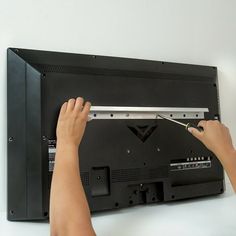 a person is working on the back side of a television with their hands and feet