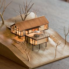 a model of a house is shown on a wooden board with trees and stairs leading up to it