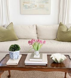 a living room filled with furniture and flowers on top of a coffee table in front of a white couch