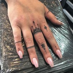 a woman's hand with a crown tattoo on the middle finger and an arrow in the middle