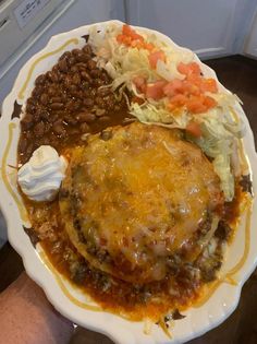 a white plate topped with meat covered in sauce and beans next to coleslaw