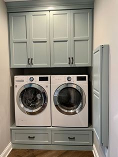 a washer and dryer in a laundry room with cabinets on the wall behind them