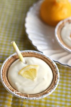 two dessert cups with lemons and whipped cream in them on a yellow checkered tablecloth