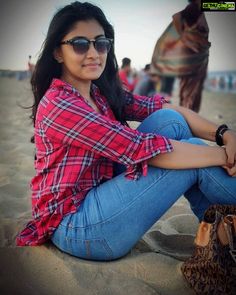 a woman sitting on the beach with her legs crossed