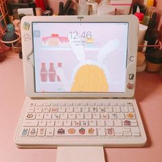 an open laptop computer sitting on top of a pink table next to bottles and cups