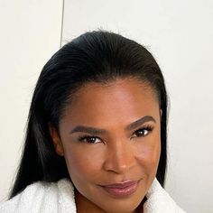 a woman in a bathrobe smiling at the camera with her hair pulled back