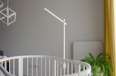 a white spiral staircase next to a potted plant in a room with grey walls