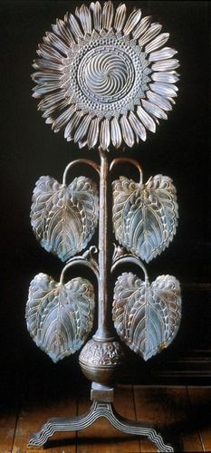 a metal vase with three sunflowers on it's sides and two hearts in the middle