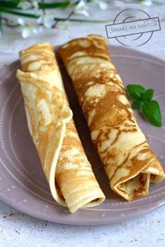 two crepes sitting on top of a purple plate next to a green plant