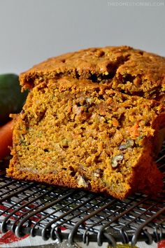 a loaf of carrot bread sitting on top of a cooling rack next to some vegetables