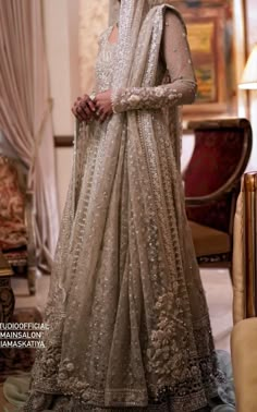 a woman in a wedding dress standing on the floor with her hand on her hip