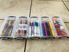 several plastic containers filled with different types of markers and pencils on a tile floor