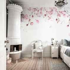 a white bedroom with pink flowers painted on the wall and a chandelier hanging from the ceiling