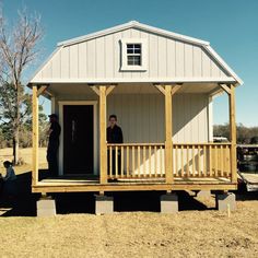 two men are standing on the porch of a tiny house that is built into the ground