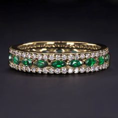 an emerald and diamond wedding ring on a black surface with white diamonds in the middle