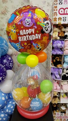 a bunch of balloons that are in a vase on a table next to some stuffed animals