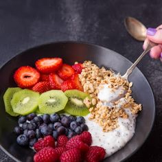 a bowl filled with yogurt, berries, kiwis and granola