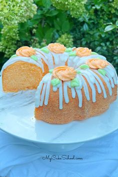 a bundt cake with frosting and orange flowers on it sitting on a white plate