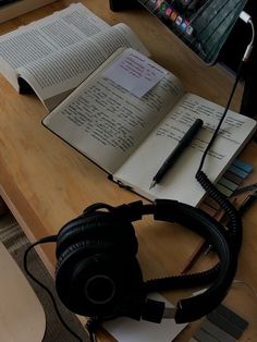 an open book sitting on top of a table next to headphones