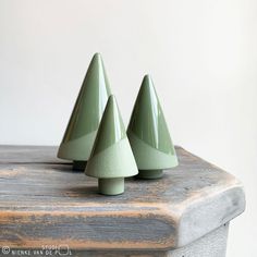 three green ceramic cones sitting on top of a wooden table