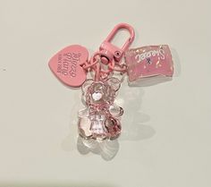 a pink teddy bear keychain with two tags attached to it