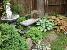 a garden filled with lots of plants and a statue in the center surrounded by greenery