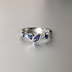 a white gold ring with blue sapphires and diamonds on the side, sitting on a table